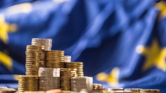 Piles of euro coins in front of EU flag