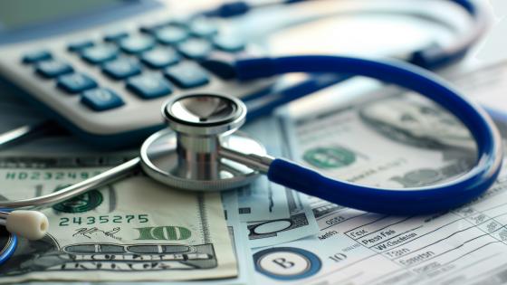 stethoscope, calculator, and US dollar bills on a medical billing statement